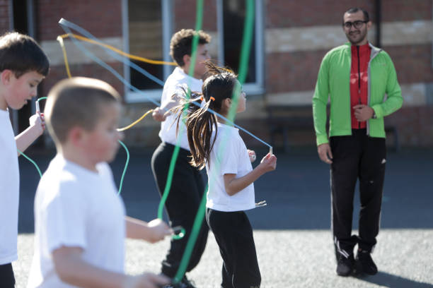 children skipping whilst teacher watches in playground