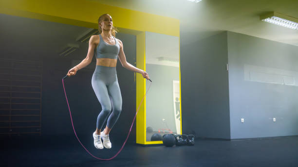 Young woman exercising on jump rope in fitness studio
