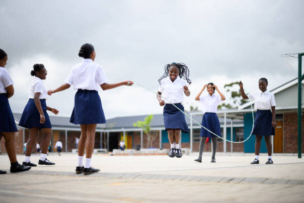 Schoolgirls skipping together in playground at school