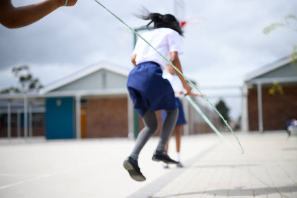 Schoolgirls skipping together in playground at school