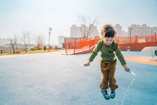 A 5-years-old asian boy plays with a jump rope in a playground